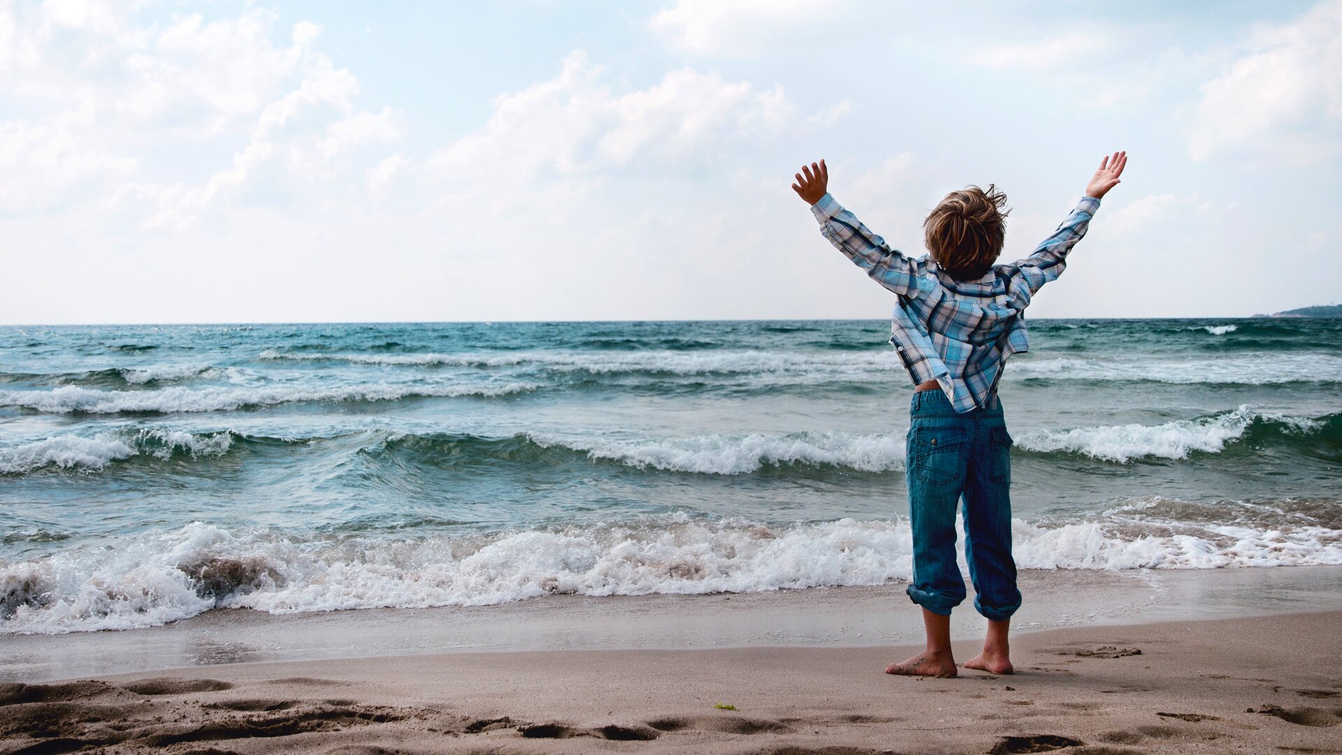 Child on a beach with hands in the air